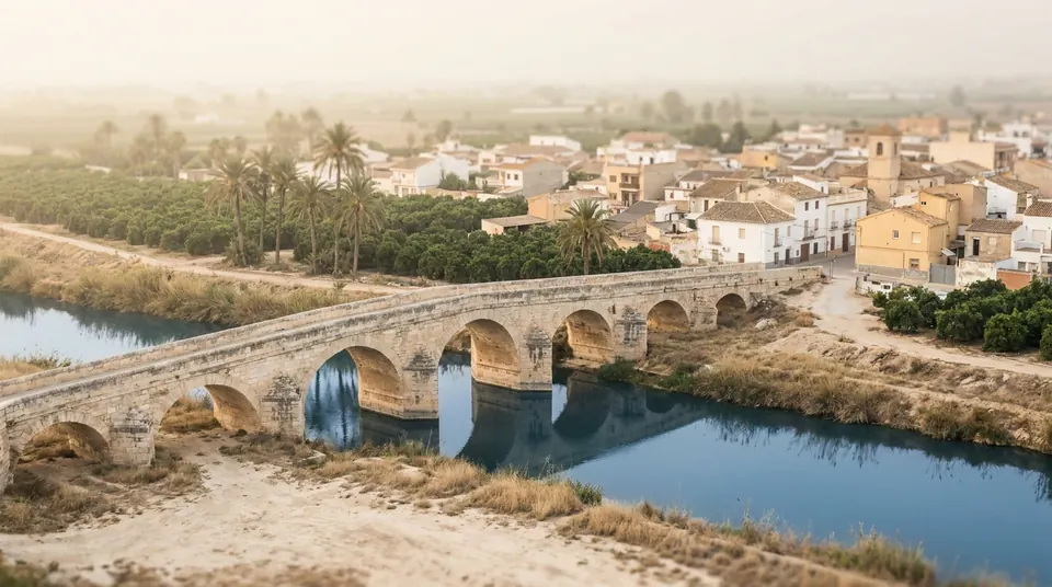 Puente de piedra sobre el río entre casas blancas